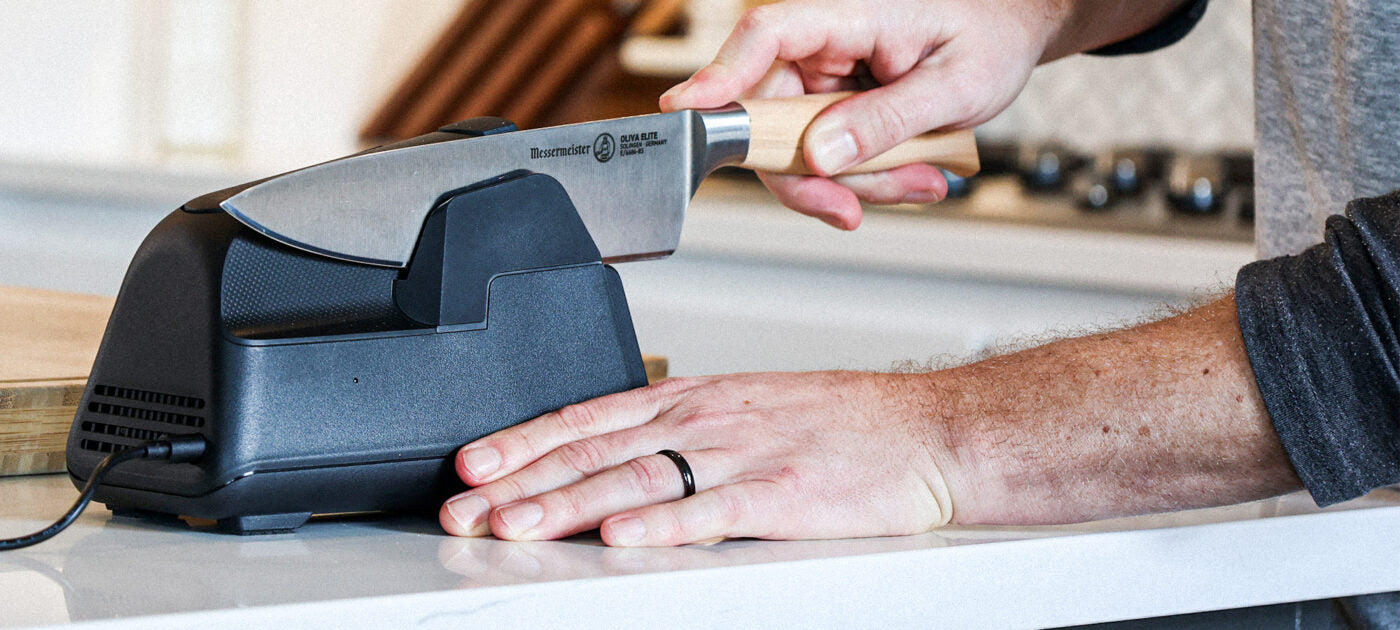sharpening kitchen knife in kitchen with electric kitchen knife sharpener